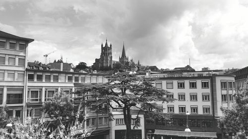 Buildings in city against cloudy sky