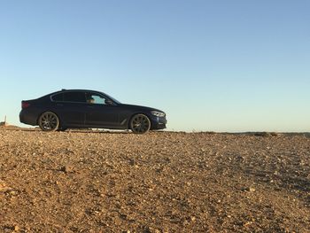 Car on field against clear blue sky