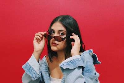 Portrait of beautiful young woman holding red wall