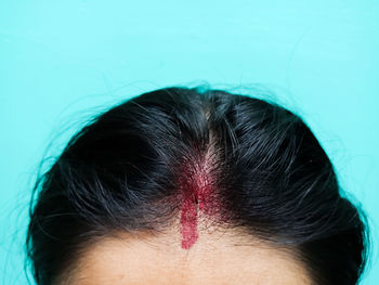 Cropped image of woman with tilaka against turquoise background