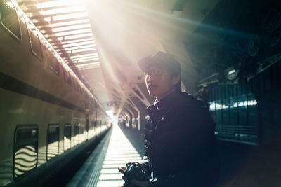 Man sitting against train at railroad station platform