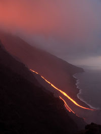 Lava flowing in sea against sky