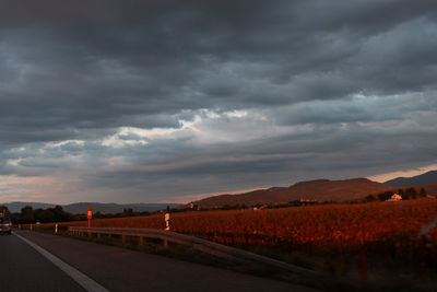 Road leading towards mountains against cloudy sky