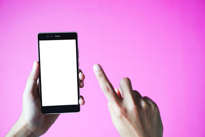 Low angle view of hand holding smart phone against pink background