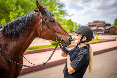 Young woman with horse standing on road