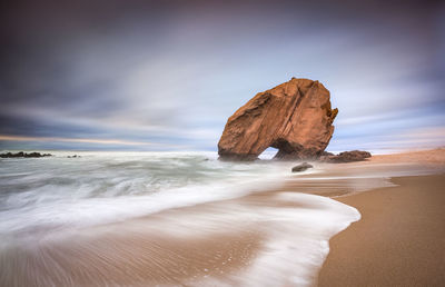 Rock formation on beach against sky