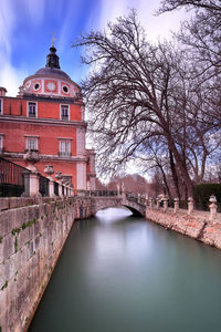 Arch bridge over canal amidst buildings against sky