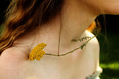 Midsection of woman with yellow flower on shoulder