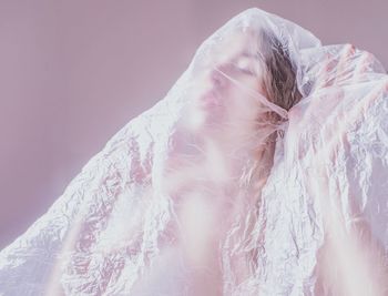 Close-up of snow covered woman against pink background