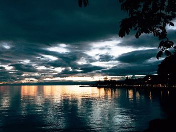 Scenic view of lake against dramatic sky during sunset