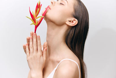 Close-up of woman holding flower against white background