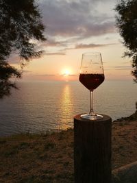 Wine glass on the sea shore against sunset sky