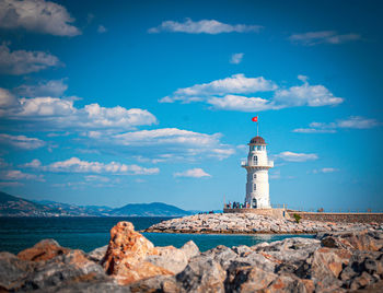 Lighthouse by sea against sky