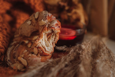 Bitten sweet pastry with almonds on a knitted orange fabric with autumn dried flowers. 