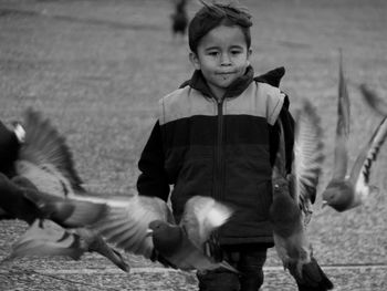 Boy walking by flying birds at footpath