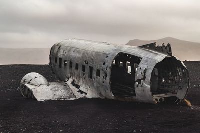 Abandoned airplane on ground against sky