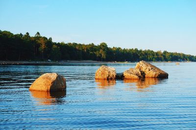 Rocks in lake against clear sky