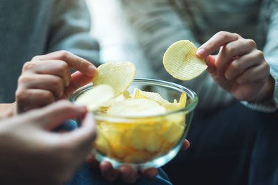 Closeup image of friends sharing and eating potato chips at home party together