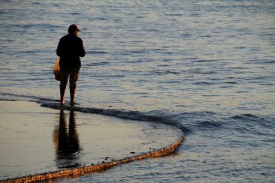 Rear view of man standing at beach
