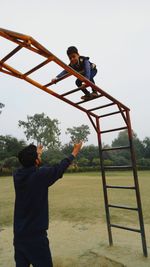 Father and son playing with outdoor play equipment at playground