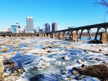 Bridge over river against clear sky during winter