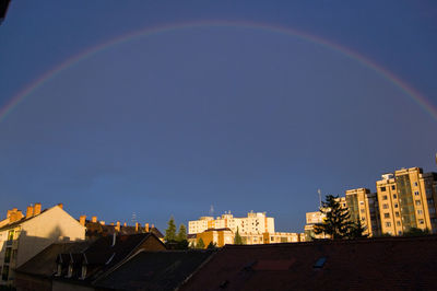 Rainbow over buildings against blue sky