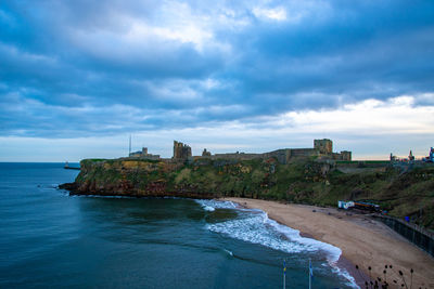 Buildings by sea against sky