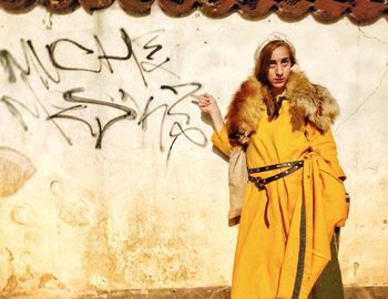 Portrait of woman standing against wall