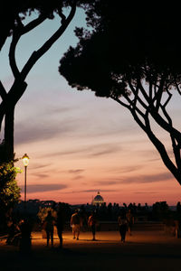 Silhouette people by tree against sky during sunset