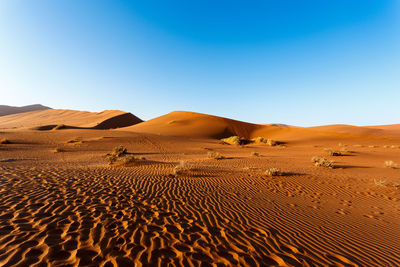 Sand dunes in desert against clear blue sky