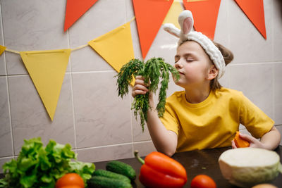 Girl in rabbit ears eat herb dill vegetables easter copy space. high quality photo