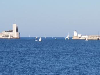 Sailboats in sea against clear sky