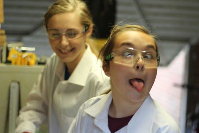 Close-up of girl making face with female friend in laboratory