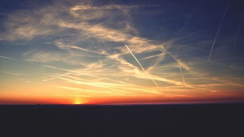 Scenic view of vapor trails in sky during sunset