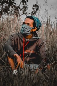 Young man looking away while sitting on land