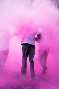 People running amidst pink powder paint in city