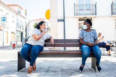 Full length of woman sitting in city