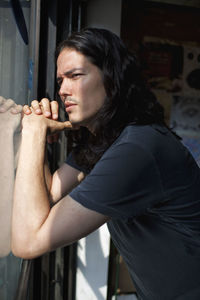 Portrait of a young man looking through a window