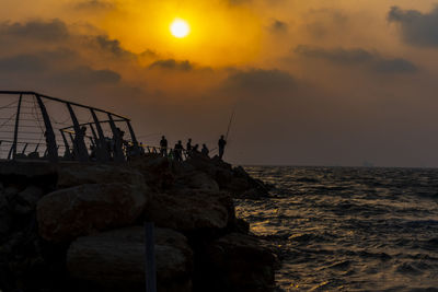 Rocks by sea against sky during sunset