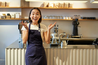 Portrait of young woman standing in kitchen