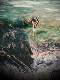 Full length of shirtless man jumping in sea