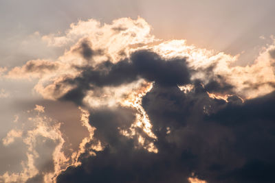 Low angle view of sunlight streaming through clouds