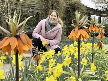 Portrait of smiling woman standing by yellow flowering plants