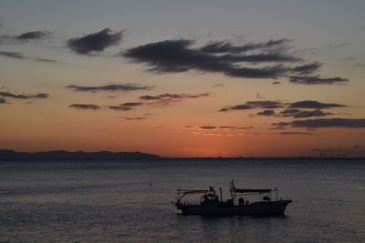 Silhouette sailboat in sea against sky during sunset