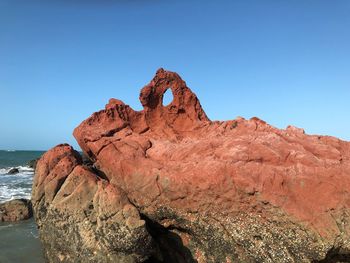 Rock formations in sea against clear blue sky