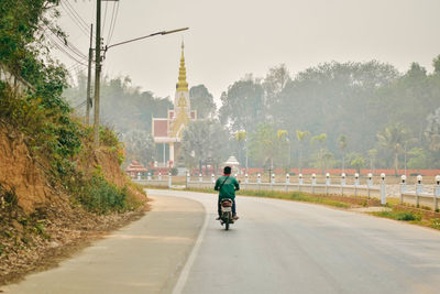 Man riding motorcycle on road against sky