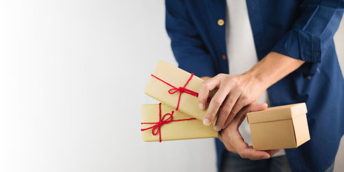 Midsection of man holding paper against white background