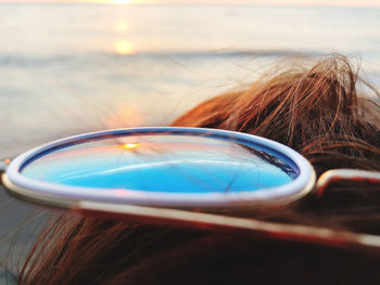 Cropped image of woman with sunglasses at beach during sunset