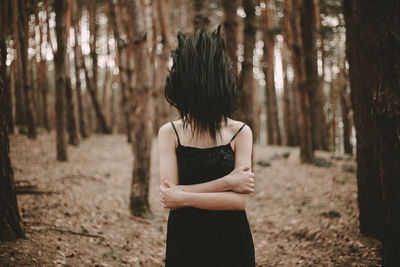 Midsection of woman with hand on tree