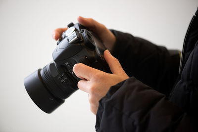 Close-up of hand holding camera over white background